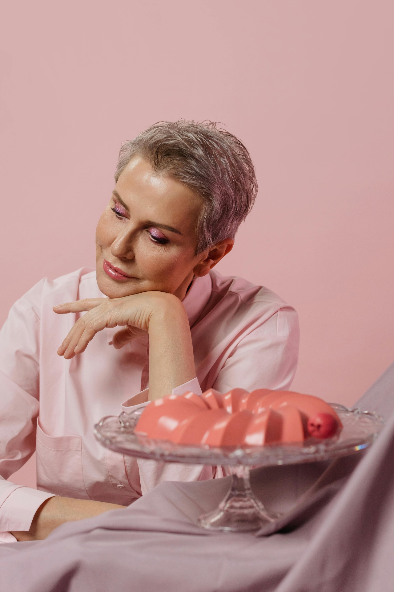 Model applying skincare against a soft pink background